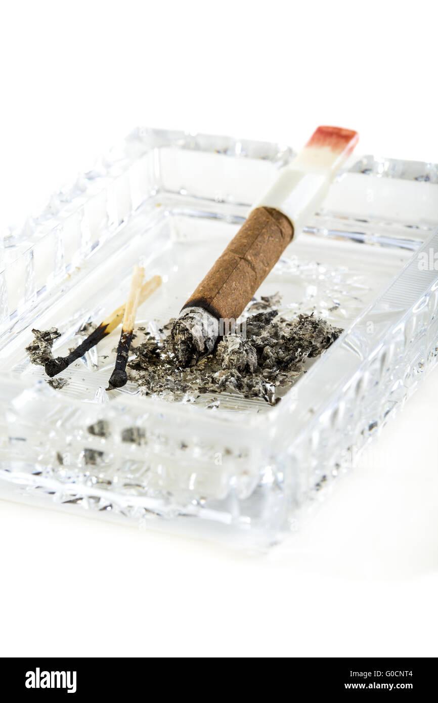 Cigarillos, burnt match in a crystal ashtray. Stock Photo