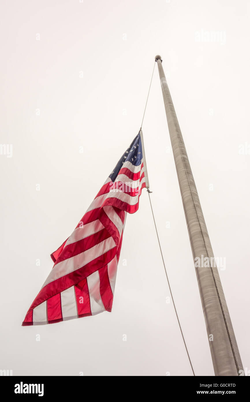 Half mast American flag concept as a symbol of the United States flying at low level to honor respect and mourning for fallen he Stock Photo