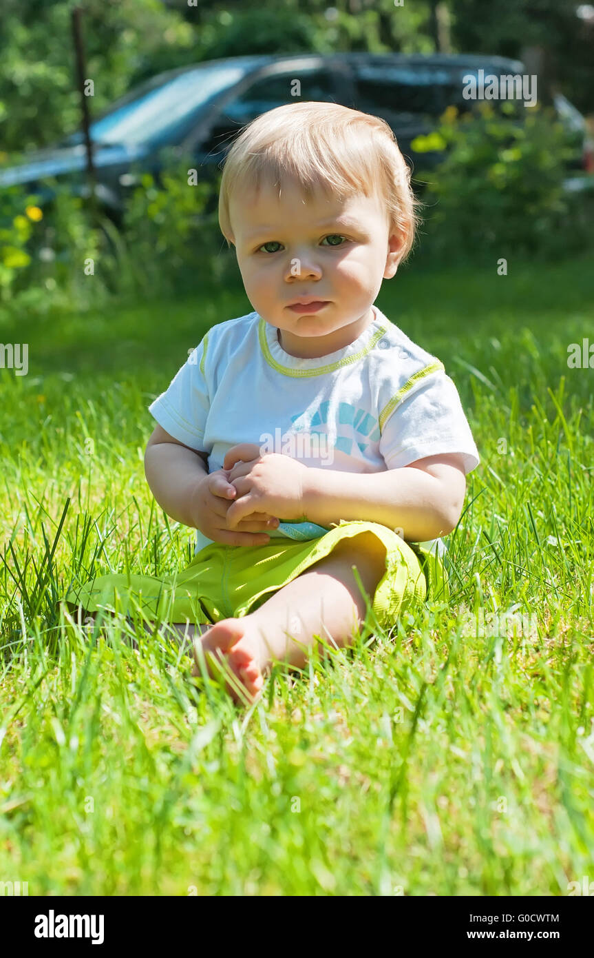 Little boy in the summer park sitting on the grass Stock Photo - Alamy