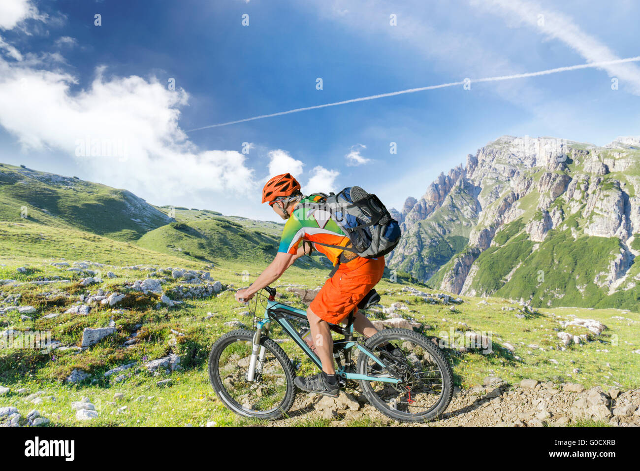 Mountain bike rider with rucksack rides a rocky single trail in the mountains Stock Photo