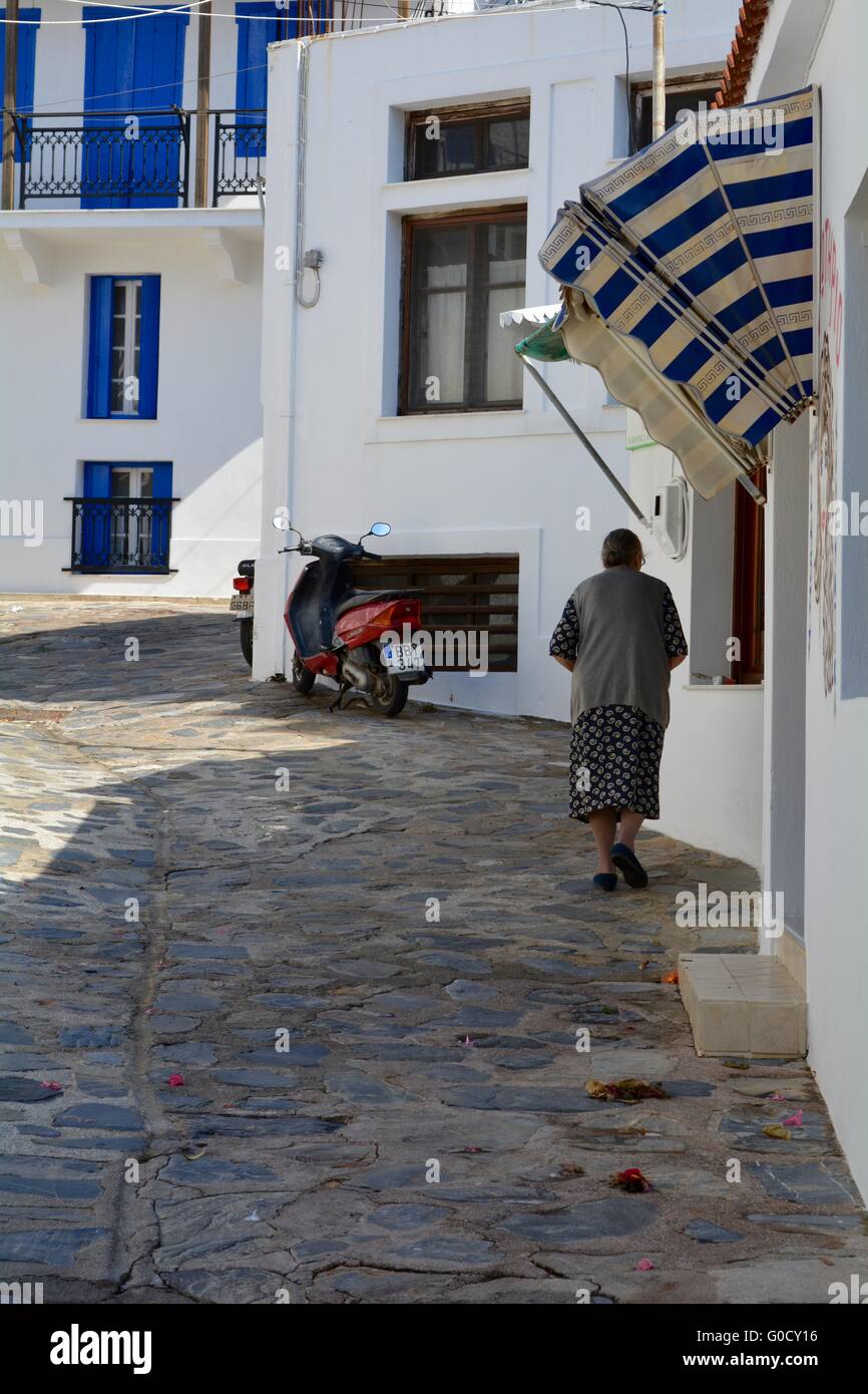 old woman walking in the shade on a street in Skopelos Greece Stock Photo