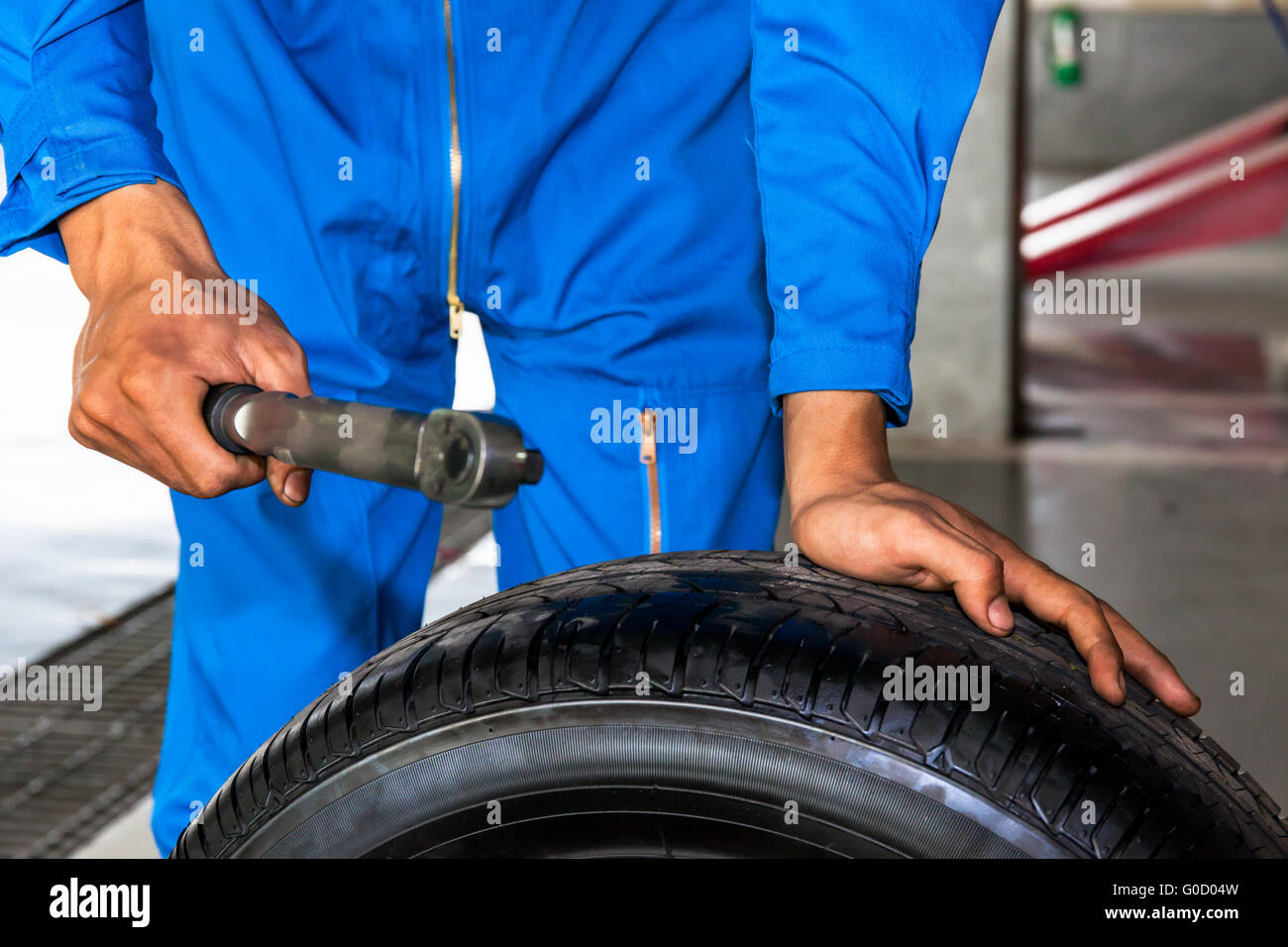 Mechanic holding a wrench and car wheel in car garage service Stock ...