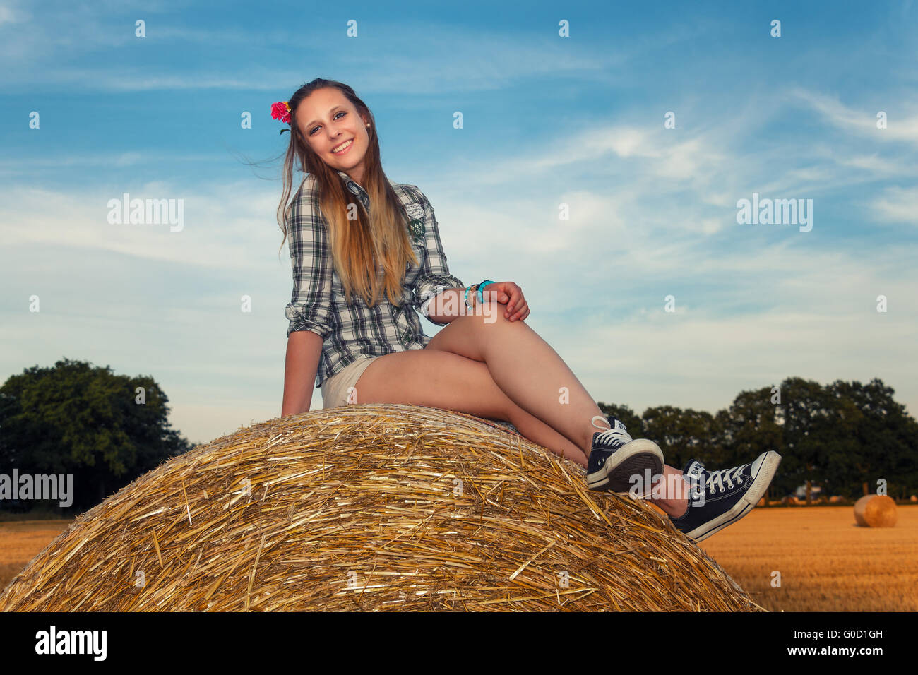 Young woman sitting on a straw bale Stock Photo