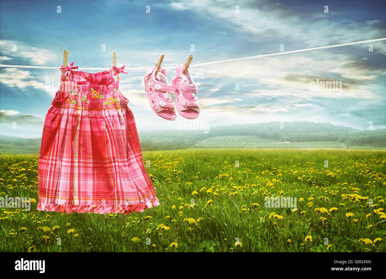 Dress and sandals on clothesline in summer fields Stock Photo