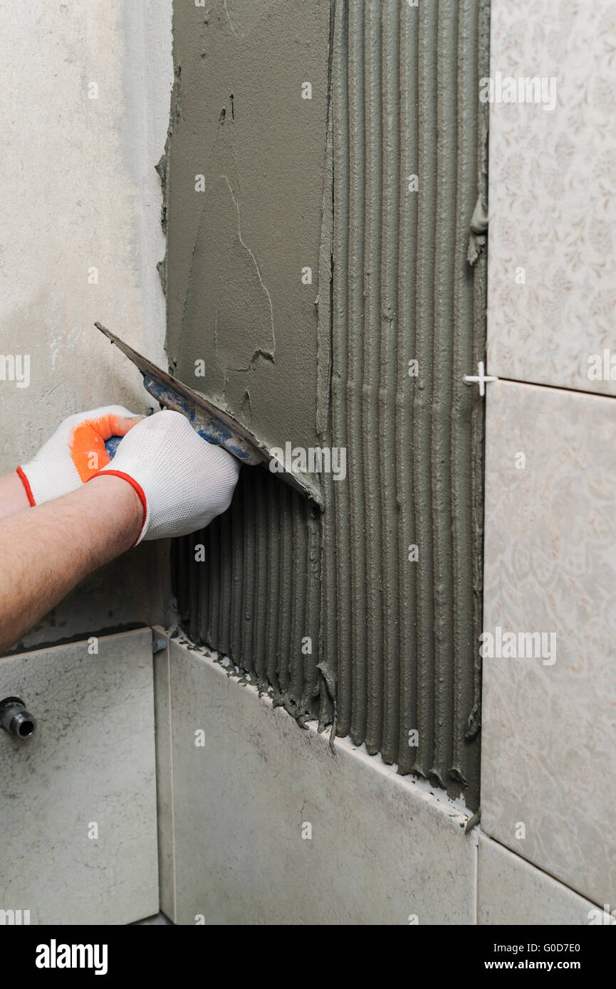Laying Ceramic Tiles. Tiler puts tile adhesive on the wall Stock Photo