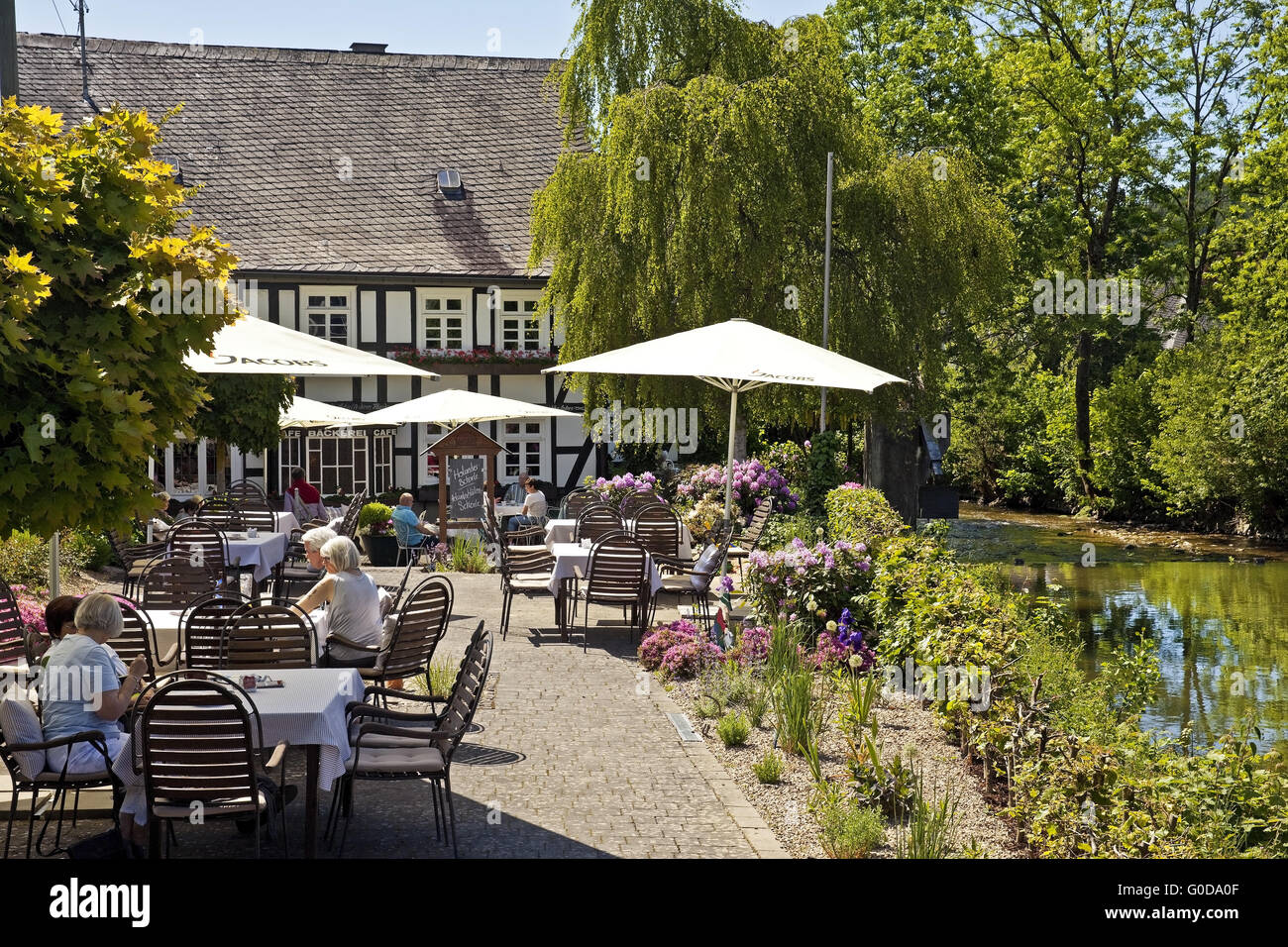 people in a garden cafe at the river Lenne Stock Photo
