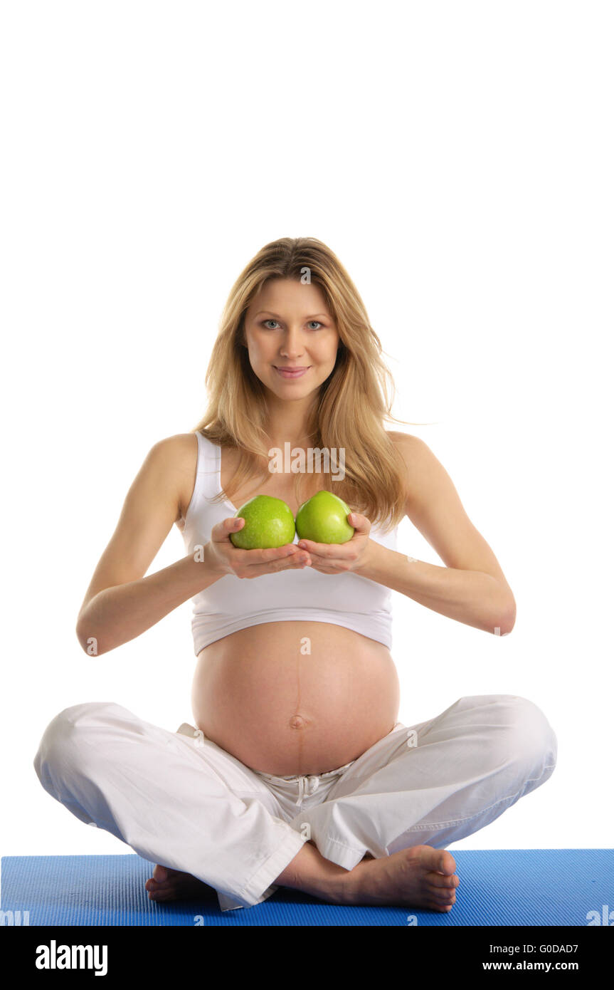 Pregnant woman practicing yoga and keeps apples Stock Photo