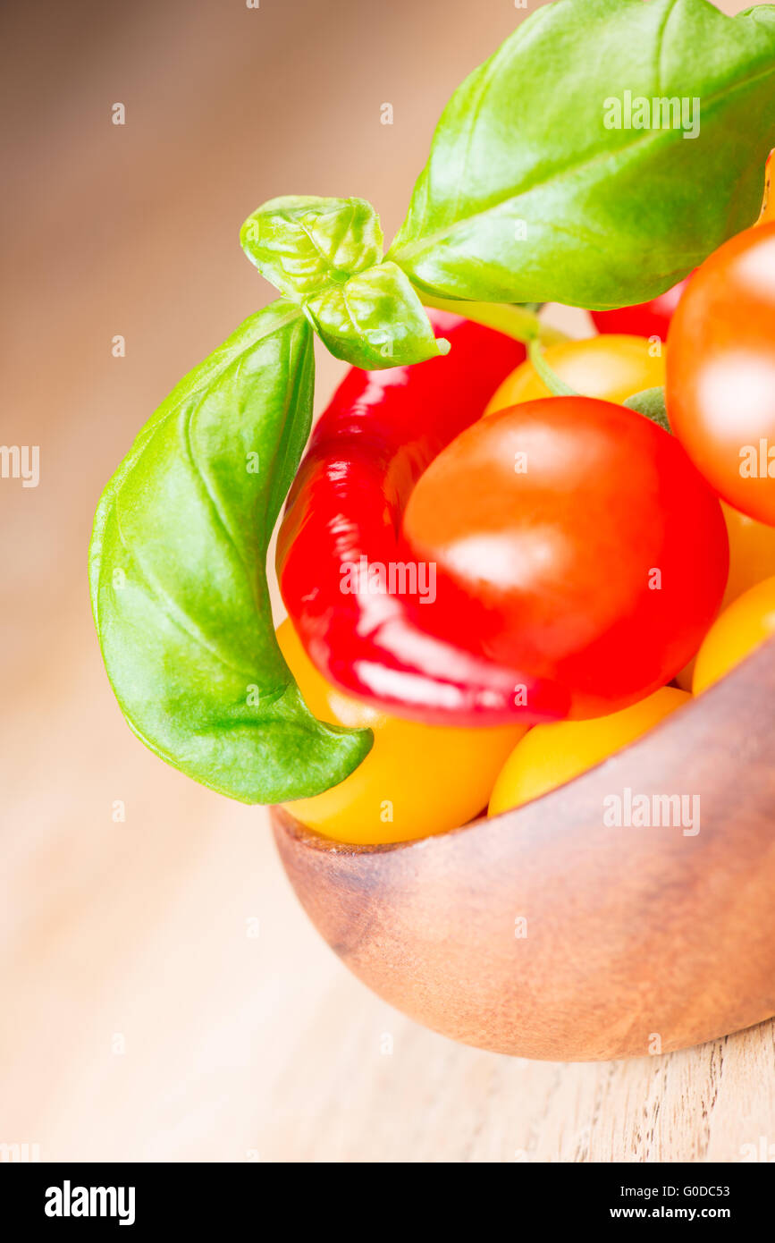 basil leafs with cherry tomatoes and pepper in wooden bowl Stock Photo