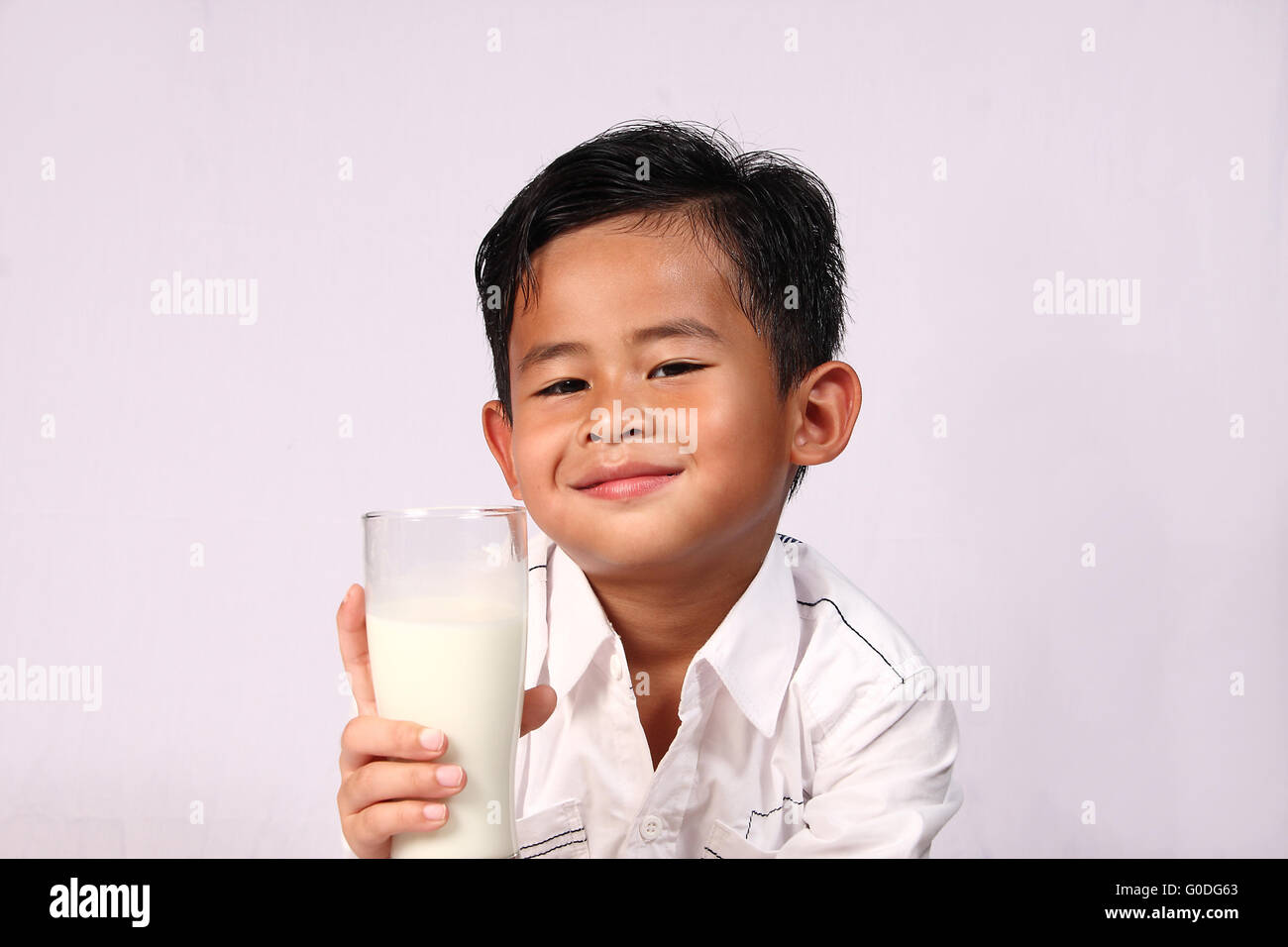 Happy and smiling Asian boy showing a glass of milk Stock Photo