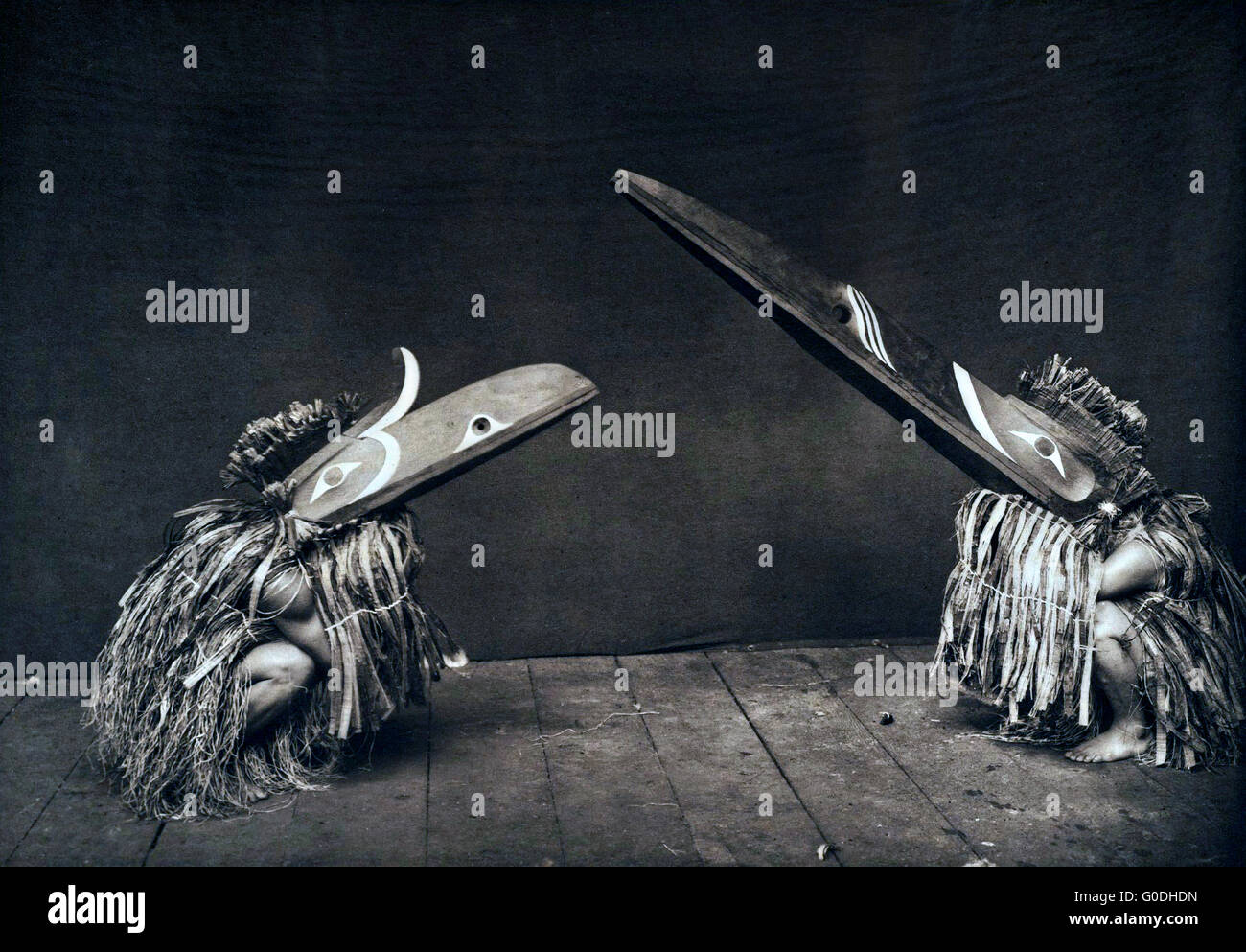 Native American Nakoaktok dancers wearing masks of the mythical Kotsuis birds during a traditional potlatch 1914 in British Columbia, Canada. The costumes represent Kotsuis and Hohhuq, servants of the man-eating monster Pahpaqalanohsiwi. The mandibles of these tremendous wooden masks are controlled by strings. Stock Photo