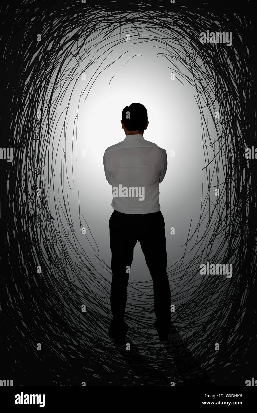 Challenge concept image rear view of a businessman starring at bright light at the end of dark tunnel Stock Photo