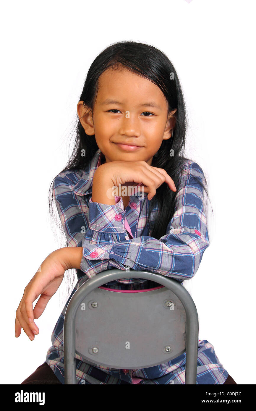 Cute little girl dressed in a short dress sits on a chair, and holding a  bouquet of flowers - Isolated on white background Stock Photo