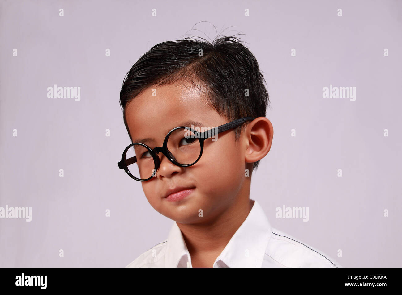 Portrait of smart young Asian boy with glasses showing his adorable smile Stock Photo