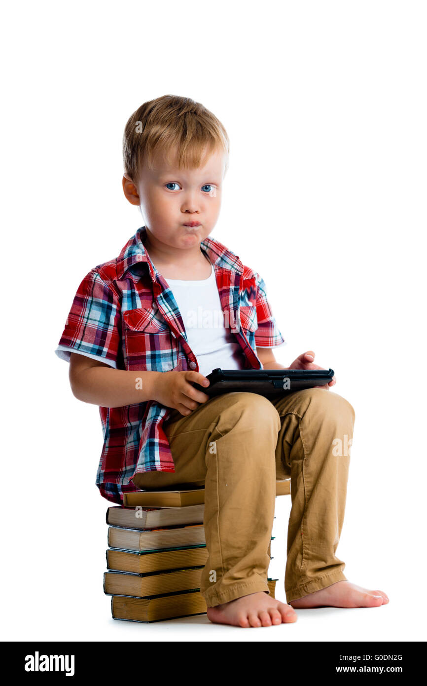Little boy with a tablet computer sitting on the books Stock Photo - Alamy