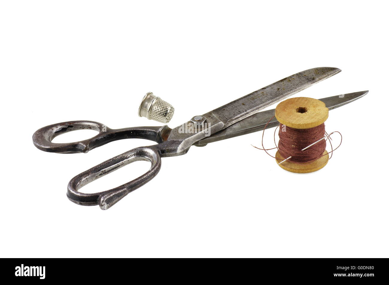 Big old garment shears, wooden spool of thread with a needle and a thimble. On a white background, isolated. Stock Photo