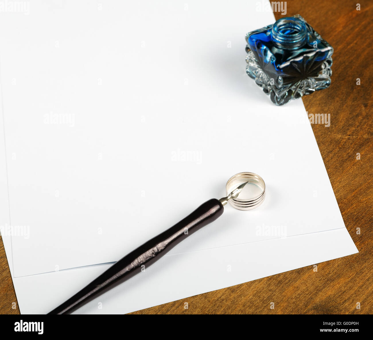 Ink pot and quill with sheets of paper on a table Stock Photo