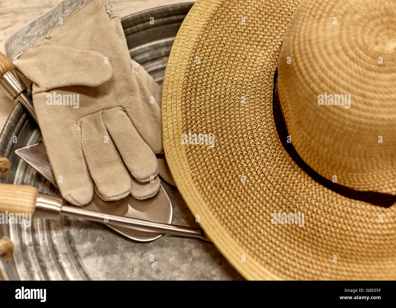 Garden work gloves, sun hat, and trowel on a tray with shallow depth of field Stock Photo