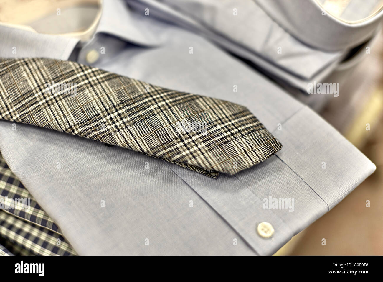 Mens folded dress shirt with necktie on shelf in department store with shallow depth of field Stock Photo