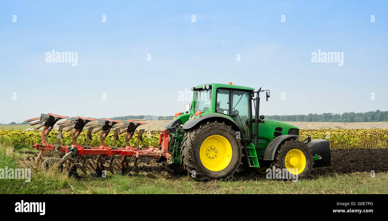 Tractor with plow in field Stock Photo