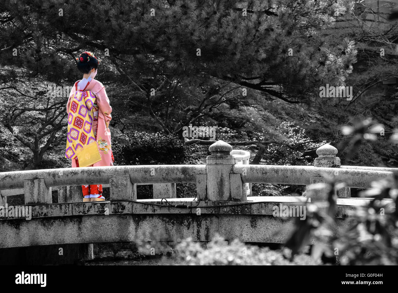 Black and white of a bridge in Kyoto with selective color on a young Geisha woman Stock Photo