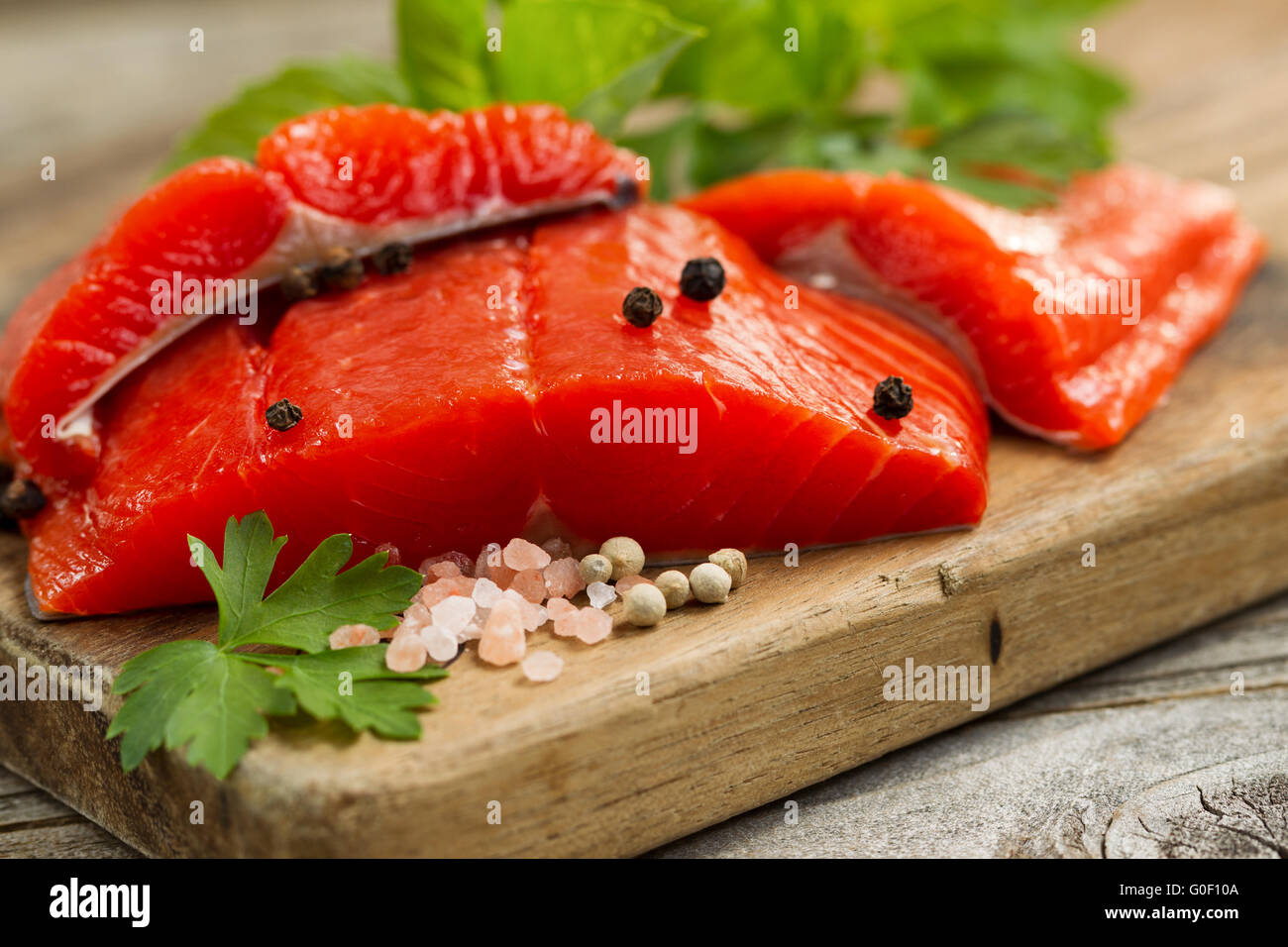 Fresh Copper River Salmon fillets on rustic wooden server with spices