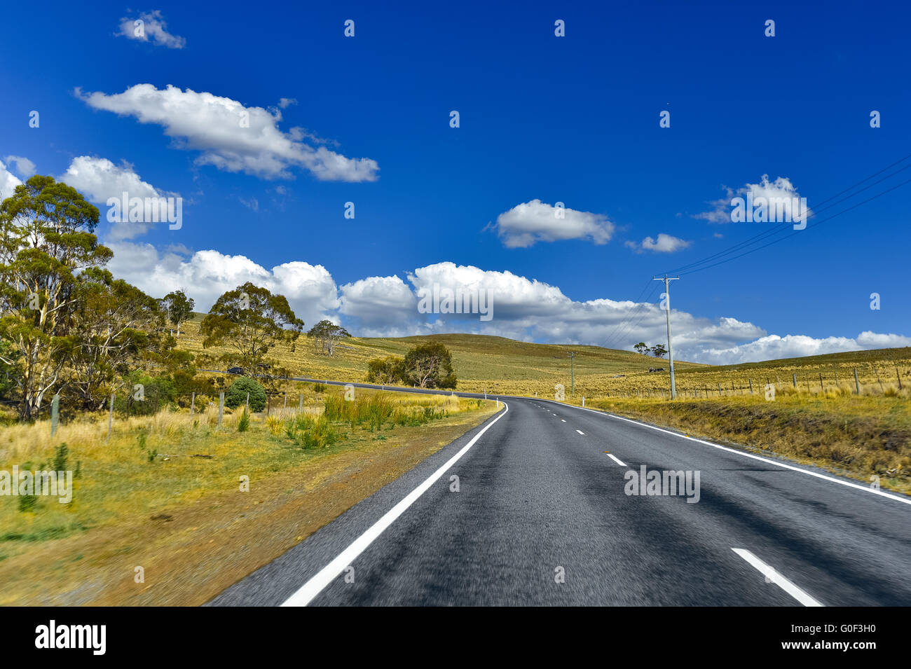 Road at countryside with blue sky and clouds, Tasmania, Australia Stock Photo