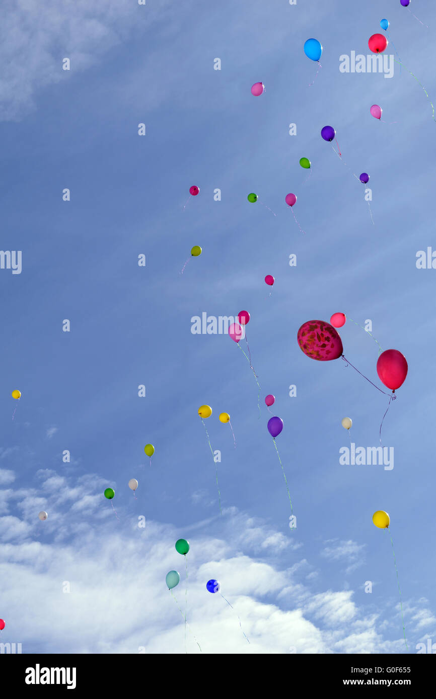 Many colored balloons fly in blue sky with clouds Stock Photo