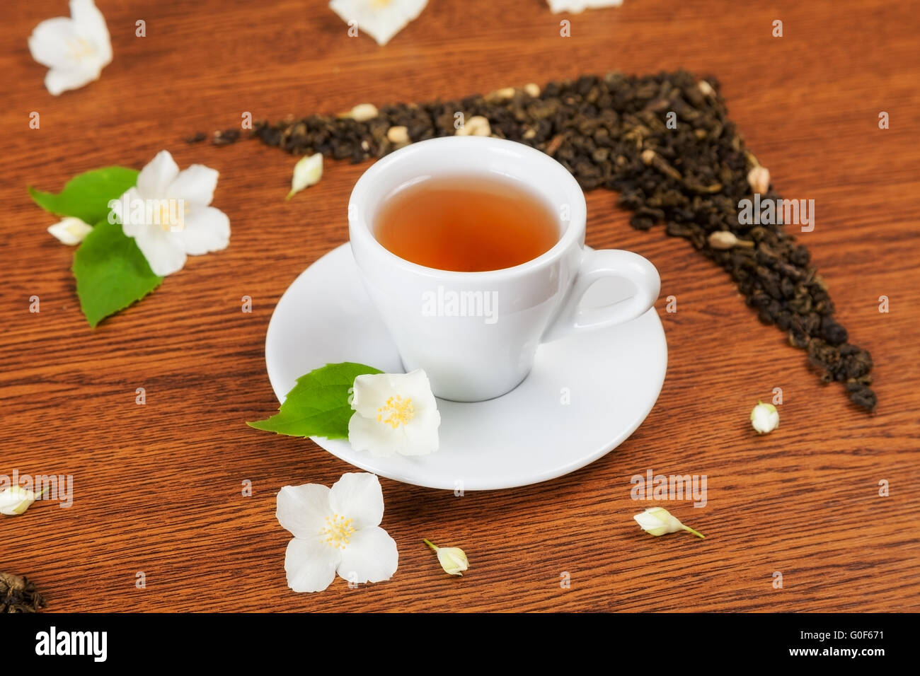 white cup and saucer with jasmine flowers on a wooden table. background Stock Photo