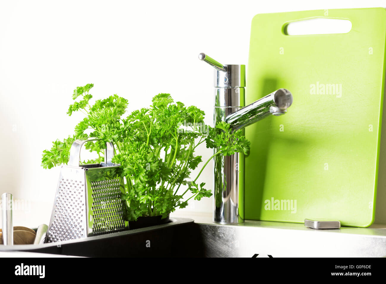 At kitchen: faucet, grater and fresh parsley Stock Photo