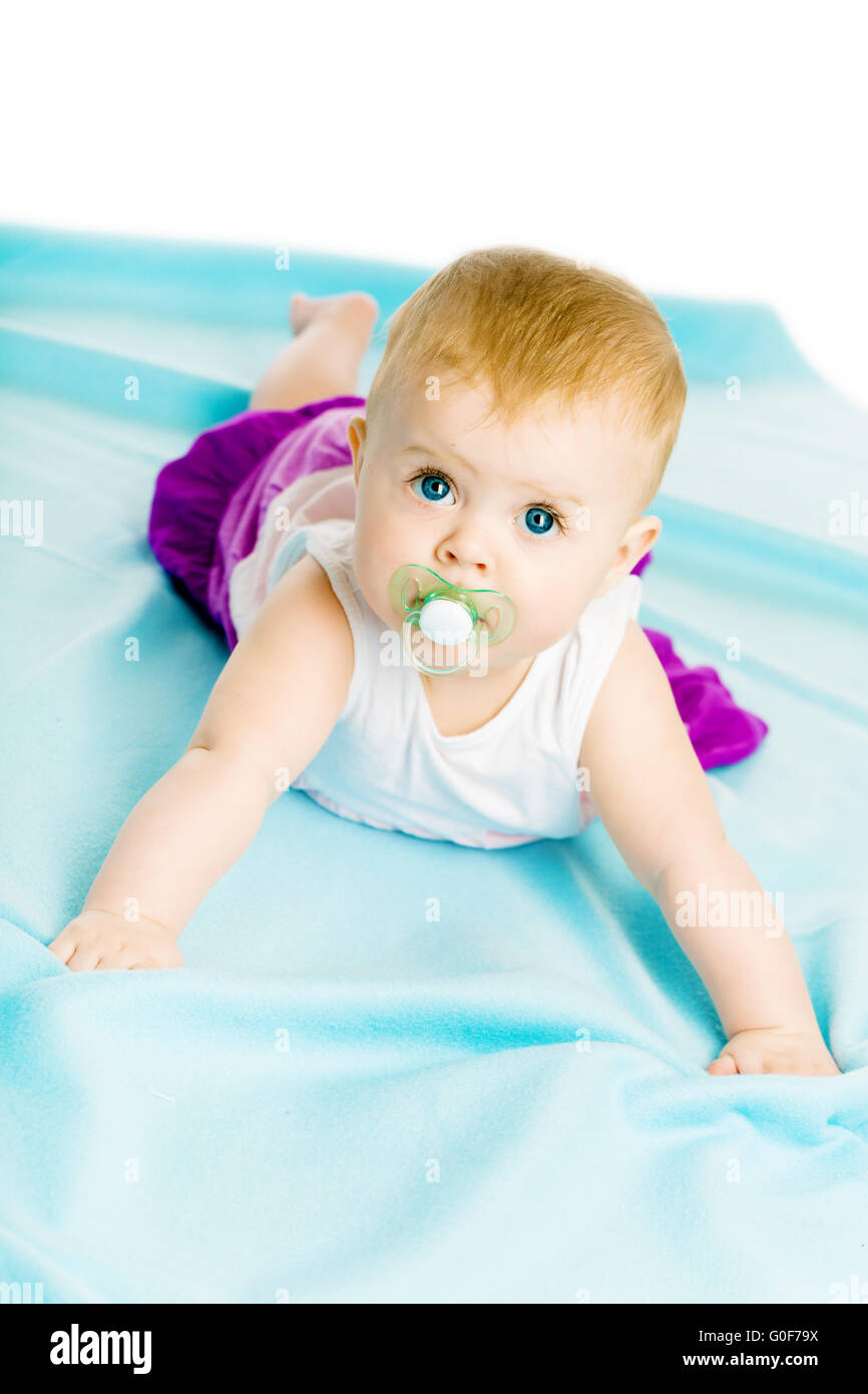 baby girl with pacifier crawling on the blue coverlet Stock Photo - Alamy