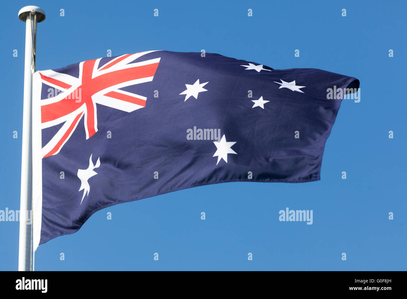 Commonwealth star and Southern cross white stars on Australian Flag flying on a mast, blue sky, Australia Stock Photo