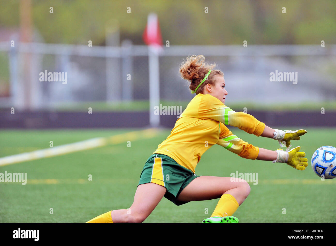 A sprawling keeper diving to make a save on a shot during a high school soccer match. USA. Stock Photo
