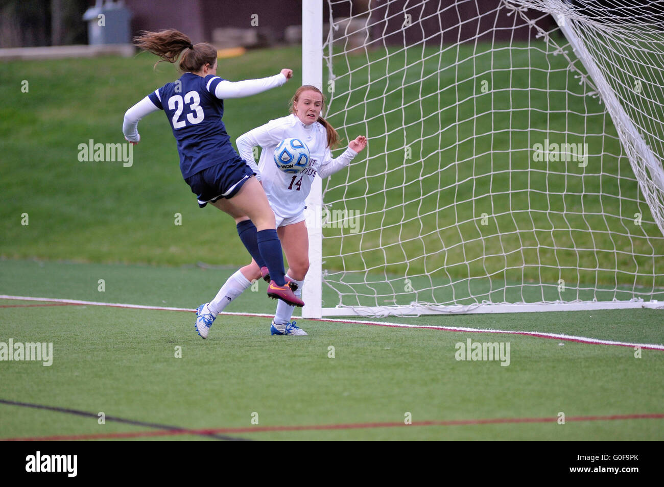 With the keeper well out of the net a player leaves her feet to score into a virtually open net during a high school match. USA. Stock Photo