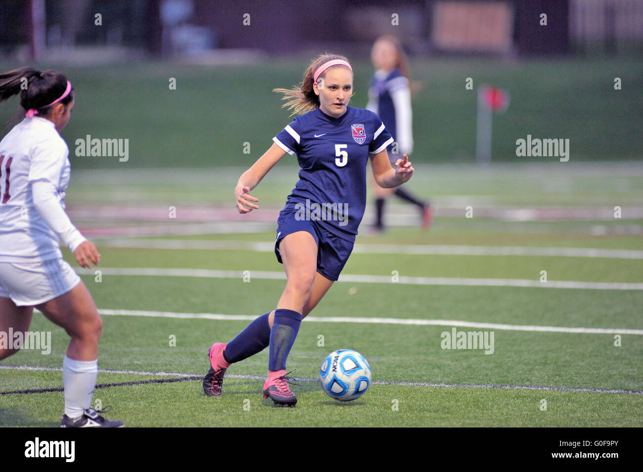 Cutting across the pitch, a player seeks a pass target down the sideline as her team was pressing for a score. USA. Stock Photo