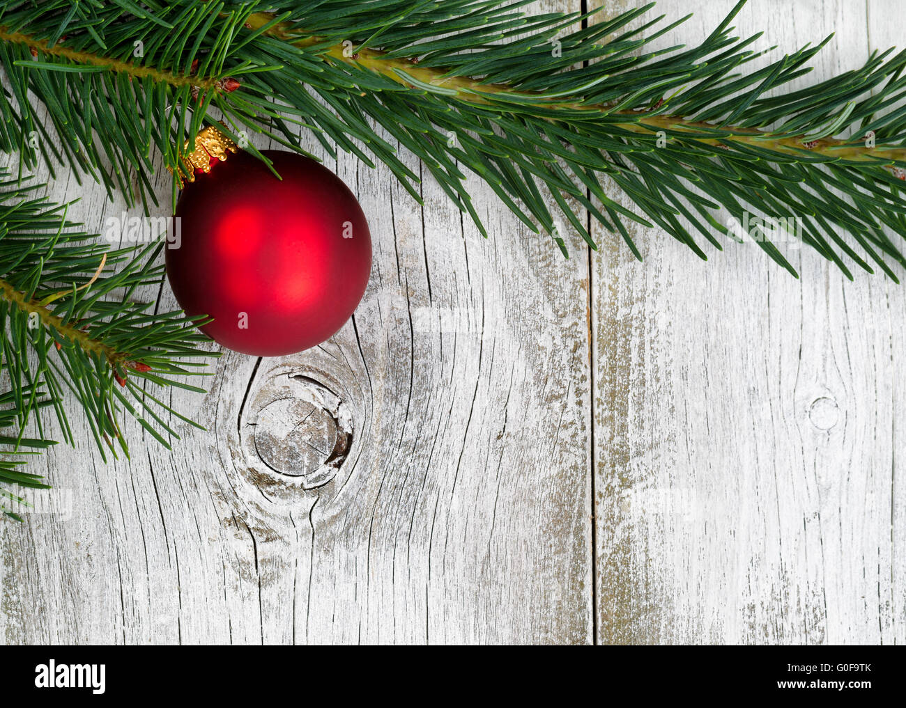 Grand fir branch with singe red ornament on rustic white wooden boards Stock Photo