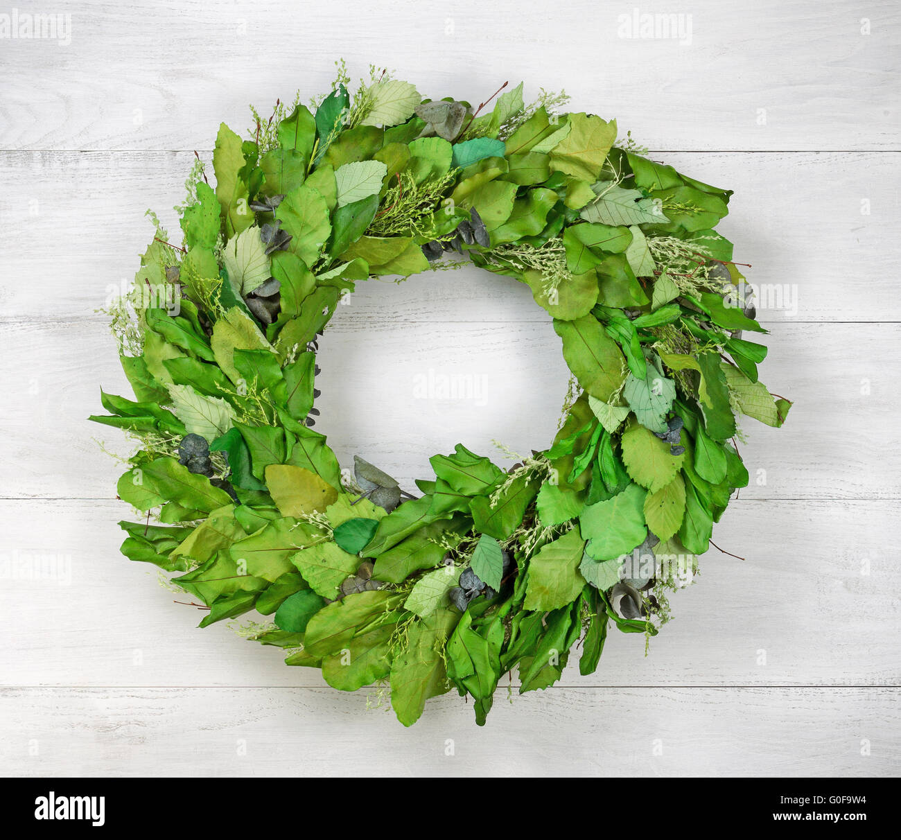 Seasonal green leaf wreath on rustic white wood Stock Photo