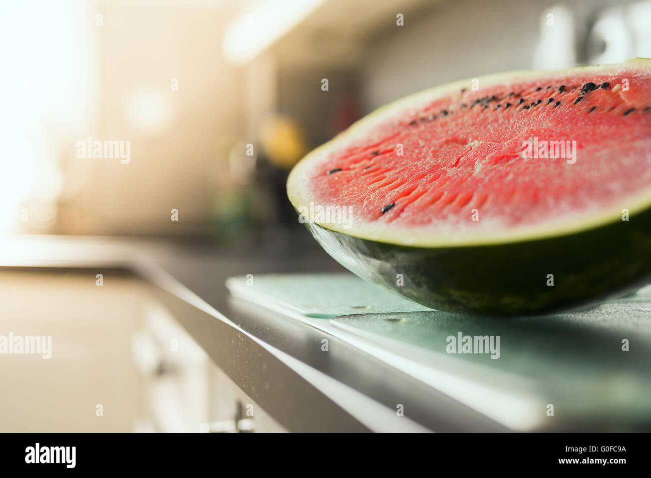 A freshly cut melon half is on the countertop in the kitchen. Stock Photo