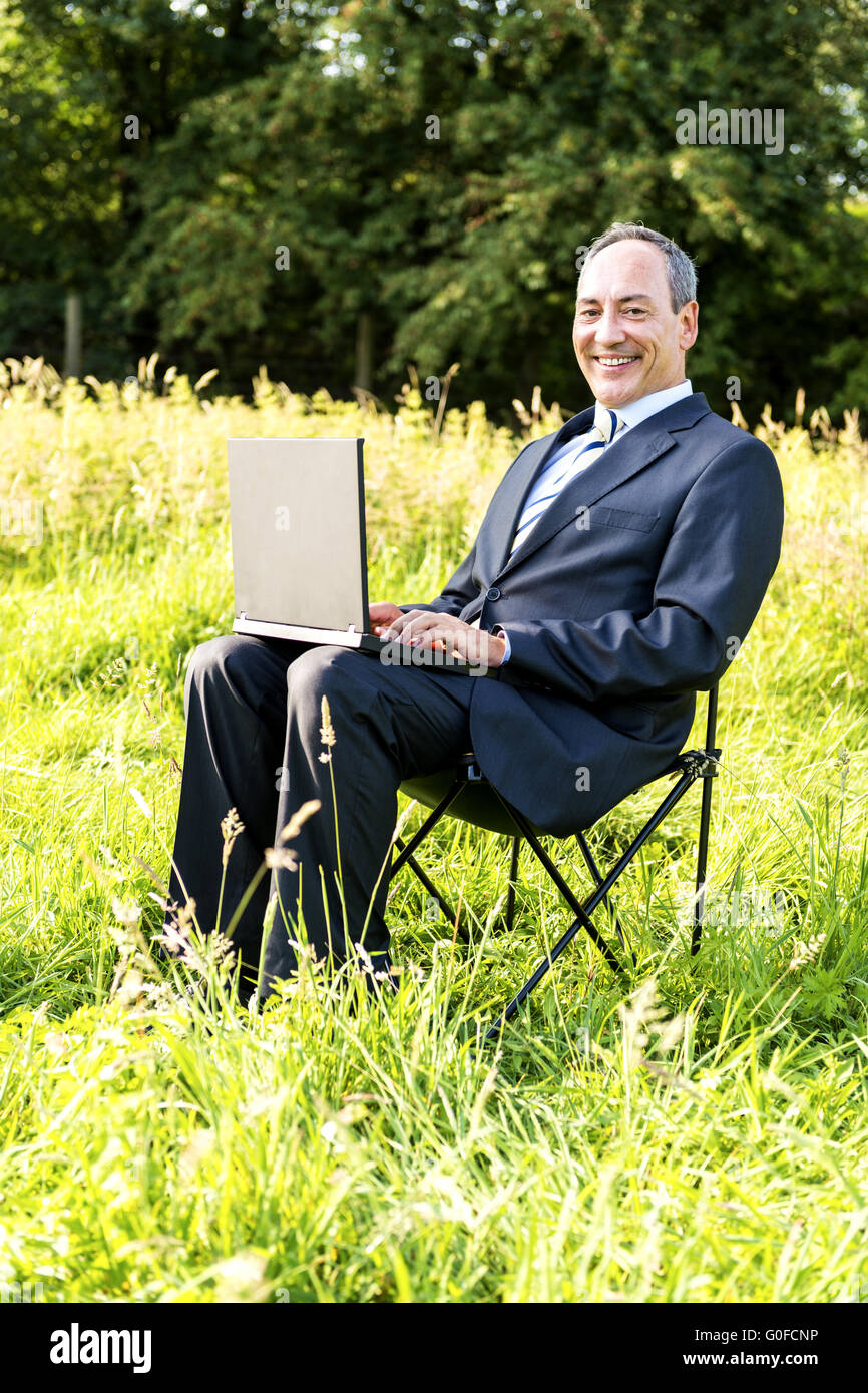 Businessman on meadow - green IT Stock Photo