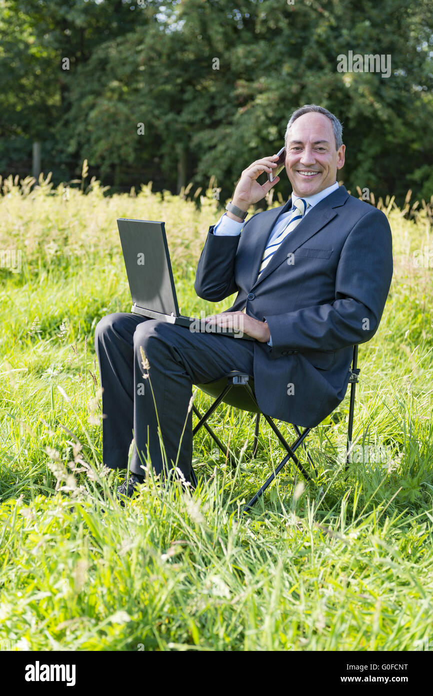Businessman on meadow - green IT Stock Photo