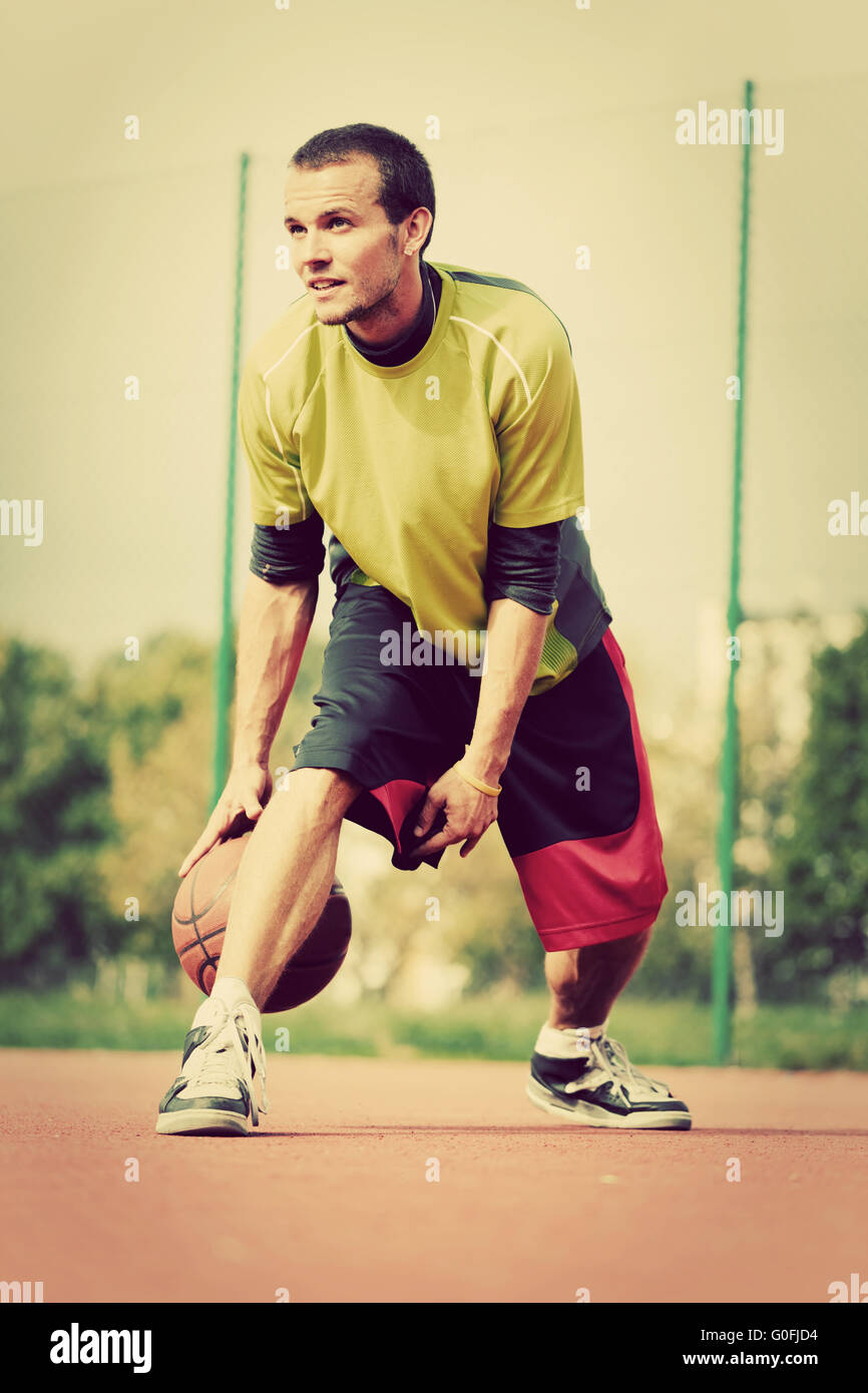 Young man on basketball court dribbling with ball. Streetball Stock Photo