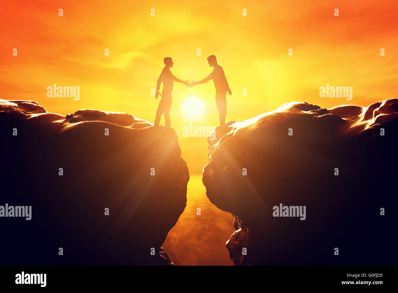 Two men shake hands over precipice between two rocky mountains at sunset. Business Stock Photo