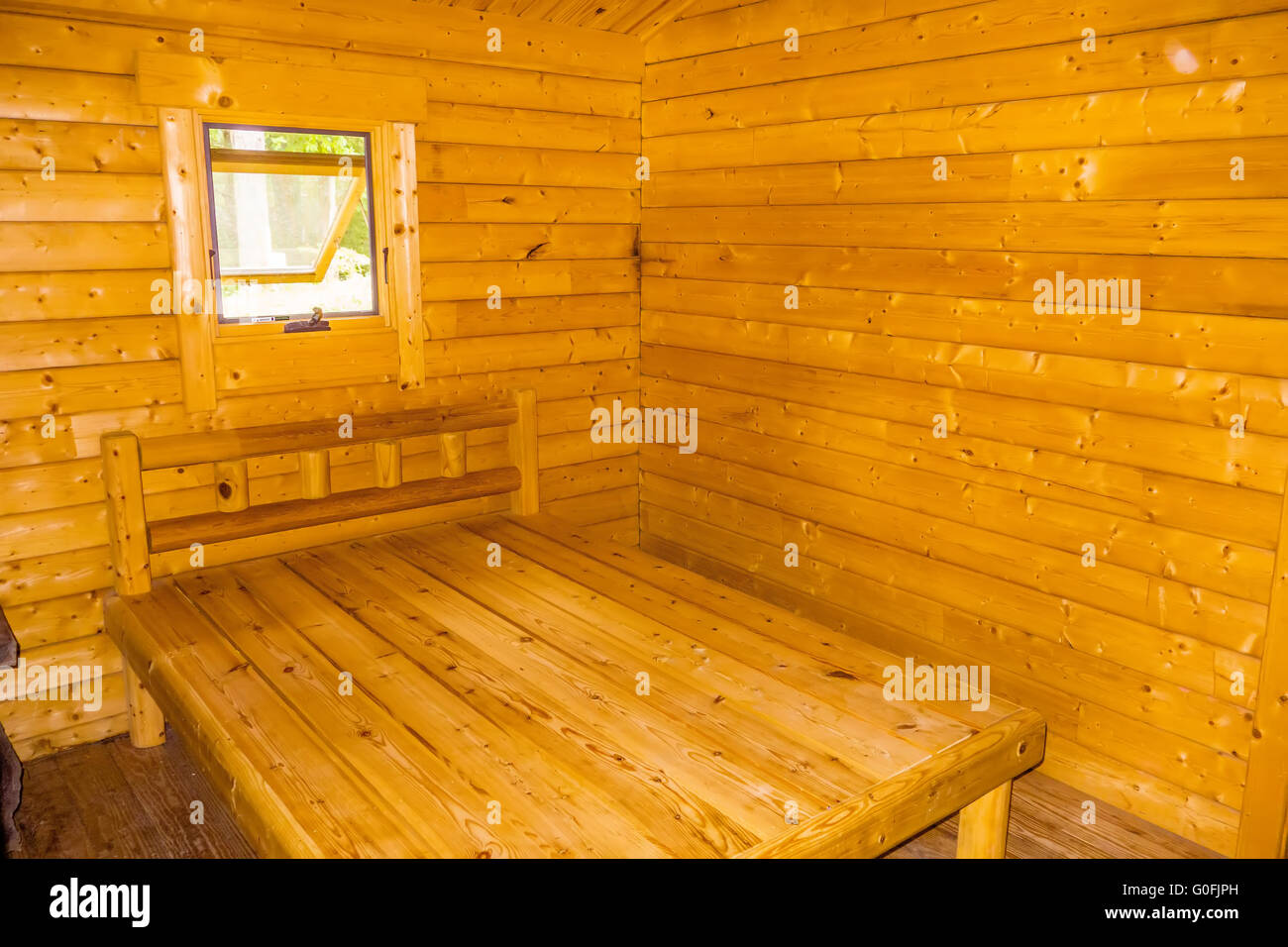 Small Log Cabin Interior With Bed And Window Stock Photo