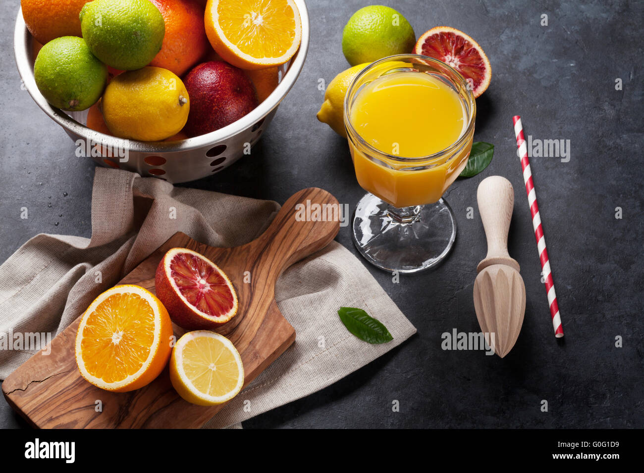 Fresh ripe citruses and juice. Lemons, limes and oranges on dark stone background Stock Photo