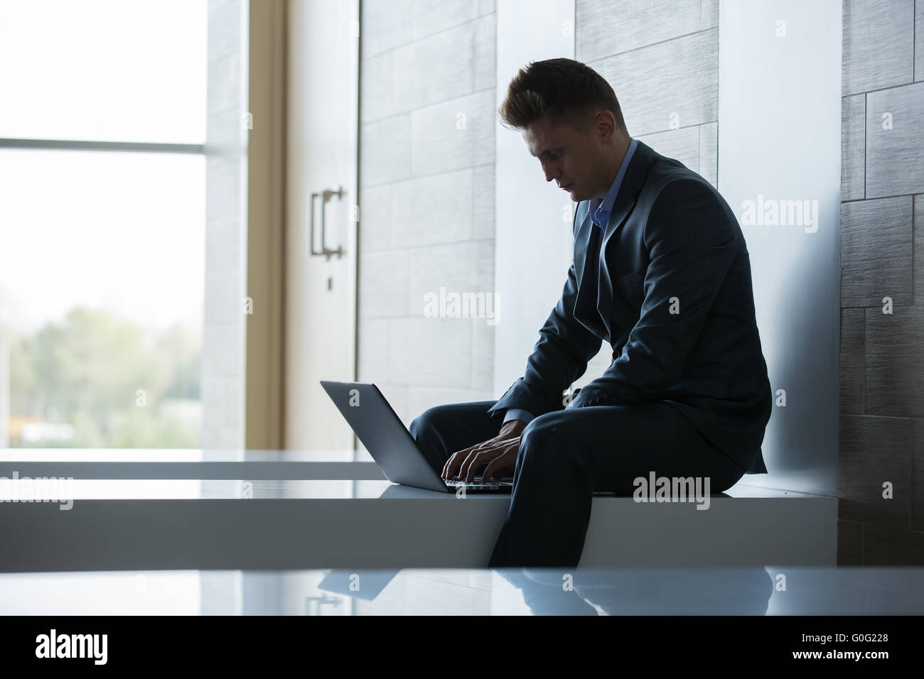 Business man sitting alone on a bench with laptop Stock Photo