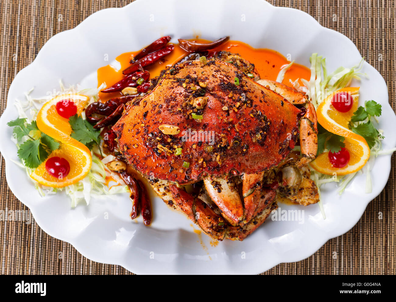Whole cooked Dungeness crab with peanut sauce and spices on white