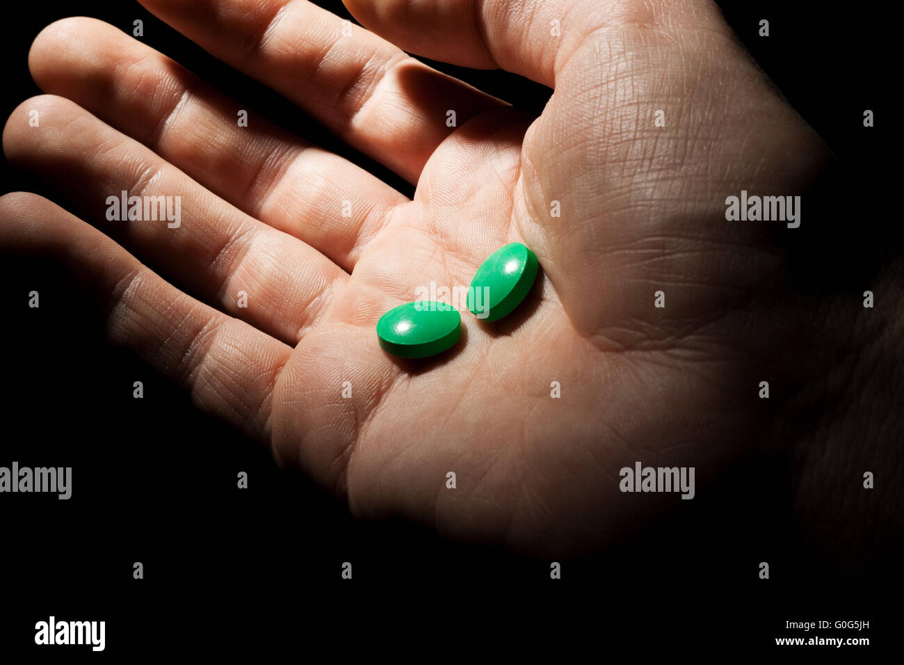 Two green pills on the opened palm Stock Photo