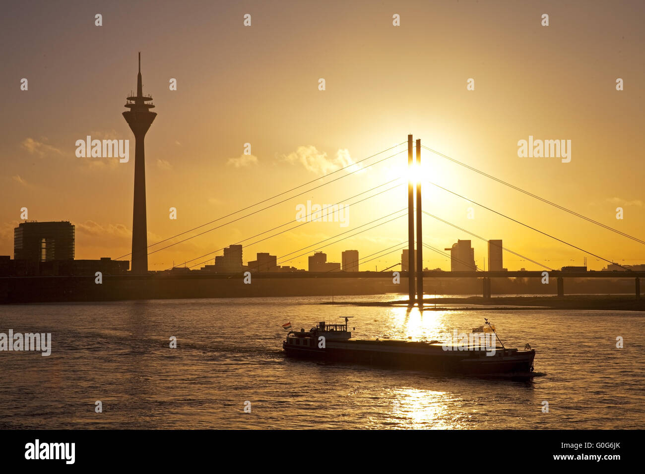 The Rhine with cargo ship, city gate, the Rhine Tower and the Rheinkniebruecke, Duesseldorf, Germany Stock Photo