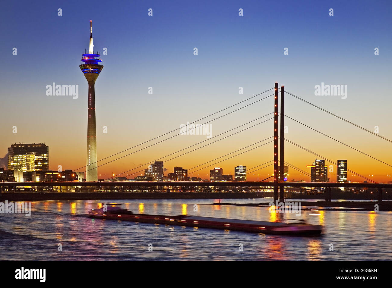 The Rhine with cargo ship, city gate, the Rhine Tower and the Rheinkniebruecke, Duesseldorf, Germany Stock Photo