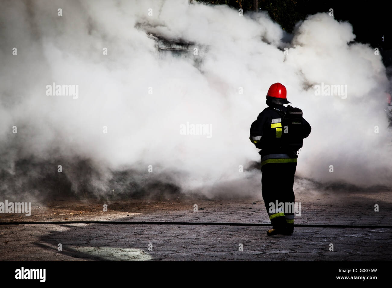 Firefighters fighting a fire of a waste place. Cloud of smoke surrounding Stock Photo