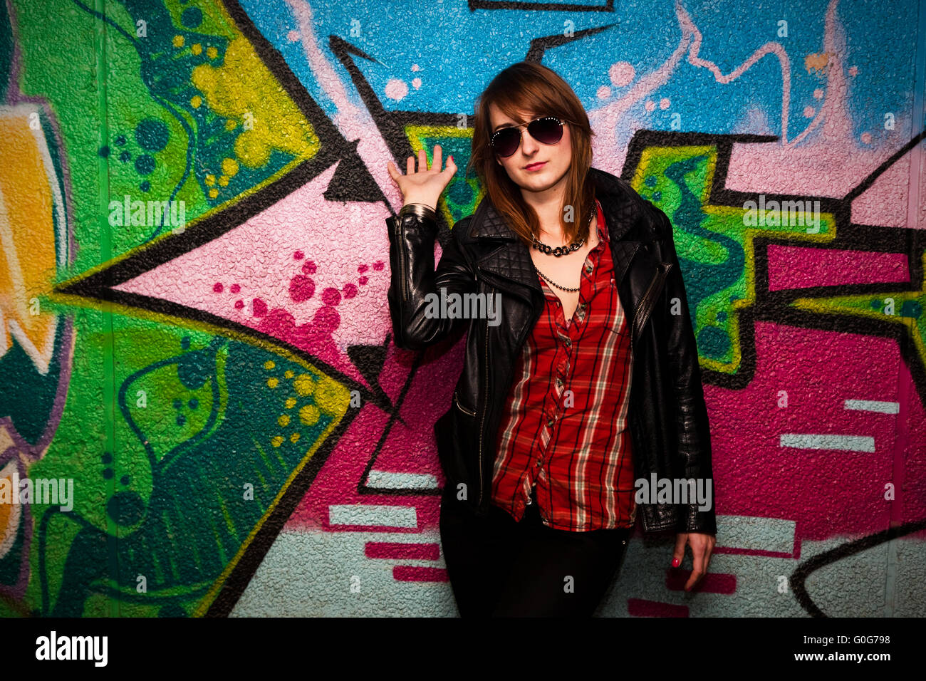 Stylish fashionable girl posing against colorful graffiti wall. Fashion Stock Photo